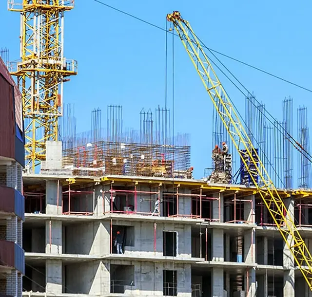 A multi-storey residential building under construction with scaffolding and a yellow tower crane
